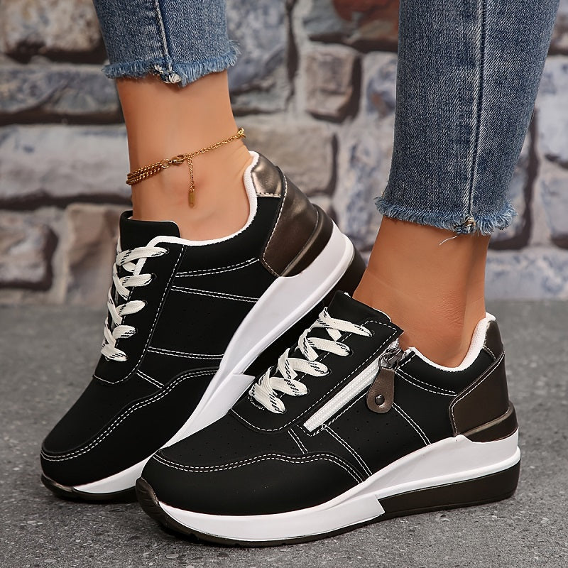 Fekete, fehér varrású sneaker oldalcipzárral, tégla háttér előtt, bokalánccal viselve 2