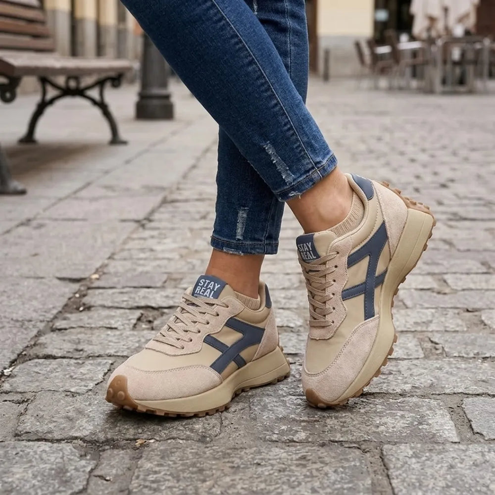 Bézs sneaker lábon, szűk farmerrel kombinálva kockaköves utcán 2