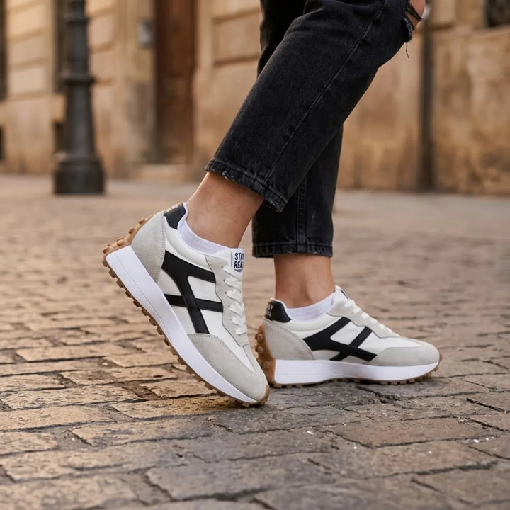 Modell lábán a sneaker kopott pincekövön, fekete farmerrel és fehér zoknival viselve 22