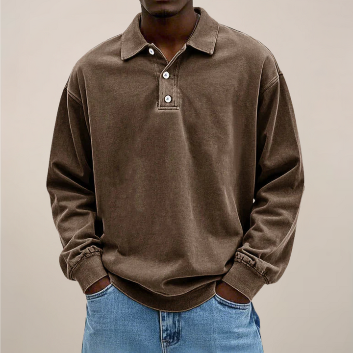 Férfi modellen elölnézetben barna hosszú ujjú galléros póló gombos patenttal, világos farmerrel, kezek a zsebekben. 3