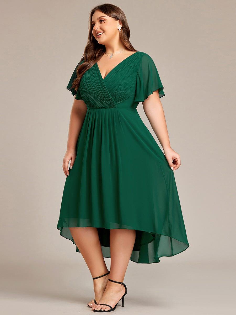 Sötétzöld ruha plus size modellen oldalnézetből, a lengő, áttetsző szegély elöl rövidebb, hátul hosszabb. 39