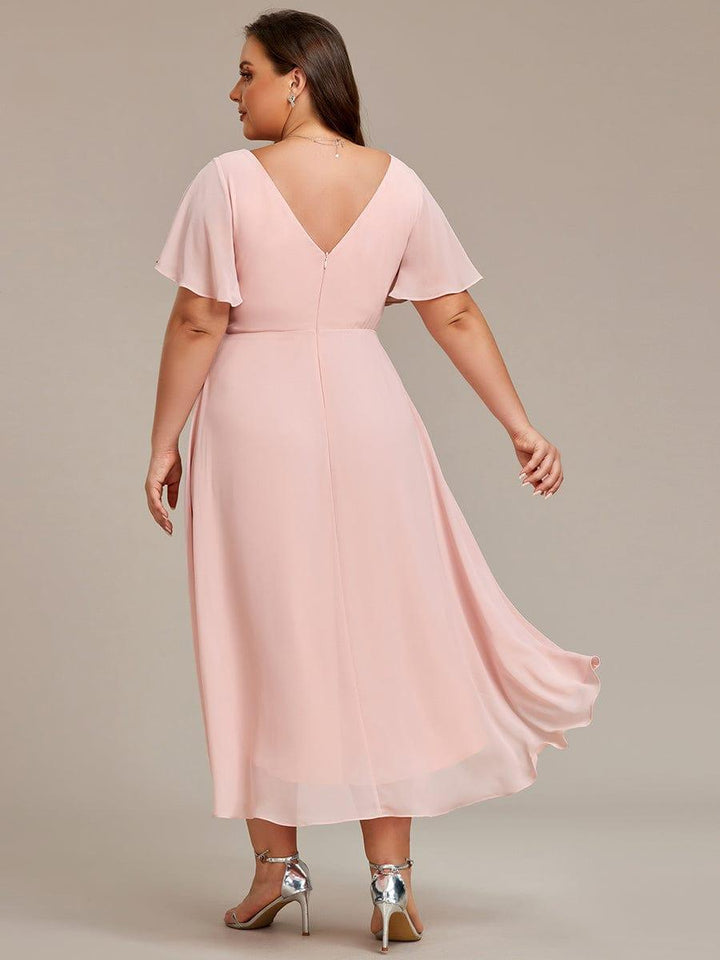 Rózsaszín ruha plus size modellen hátulról, mély V-hátkivágás, középső cipzár és lengő hátsó szegély. 32