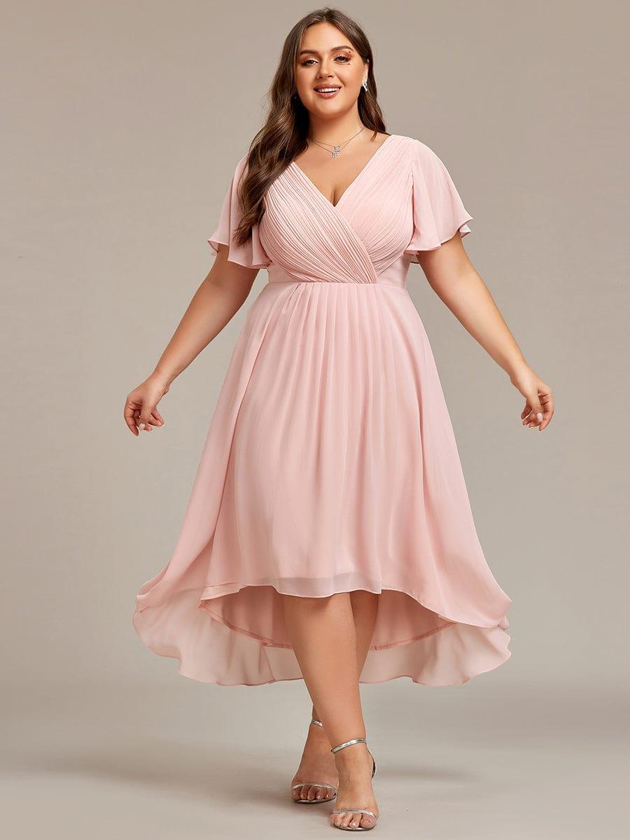 Rózsaszín ruha plus size modellen, kitárt karokkal, jól látható a redőzött fűző és az aszimmetrikus szoknya. 35