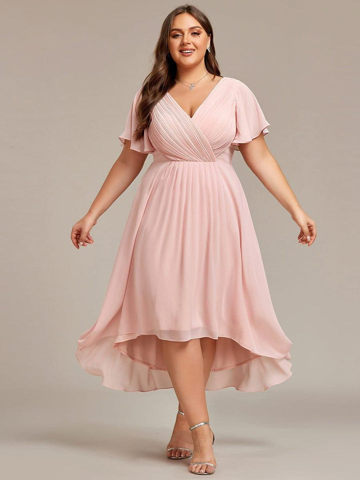 Rózsaszín ruha plus size modellen, kitárt karokkal, jól látható a redőzött fűző és az aszimmetrikus szoknya. 35