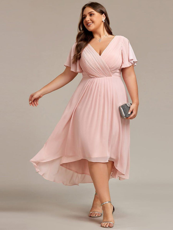 Rózsaszín ruha plus size modellen, mozgás közben lengő szoknyával, csillogó kistáskával és ezüst szandállal. 31