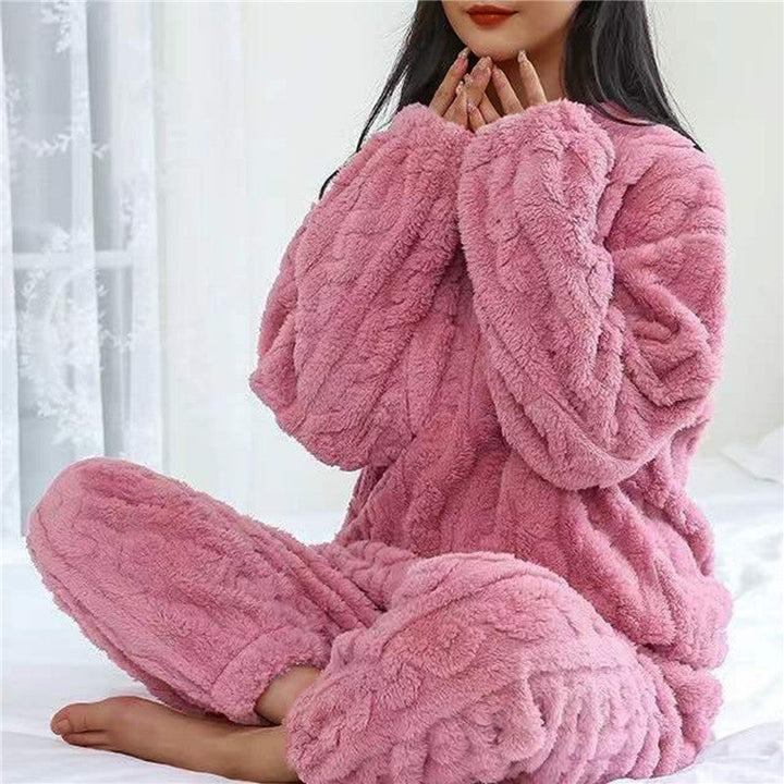 Rózsaszín plüss pizsamaszett törökülésben ülő modellen, kezeit az álla elé emeli 6