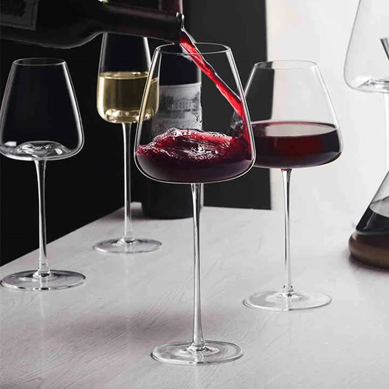 Vörösbort töltenek az egyik pohárba, mellette fehérboros és vörösboros poharak állnak az asztalon 2