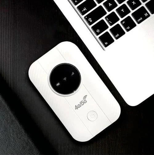 Felülnézet: a fehér router egy fekete asztalon fekszik egy laptop billentyűzete mellett 5