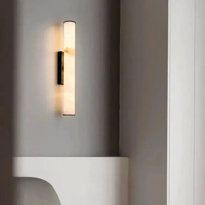 Világító márvány falilámpa fekete foglalattal szürke falon, alatta fehér ívelt polc. 20