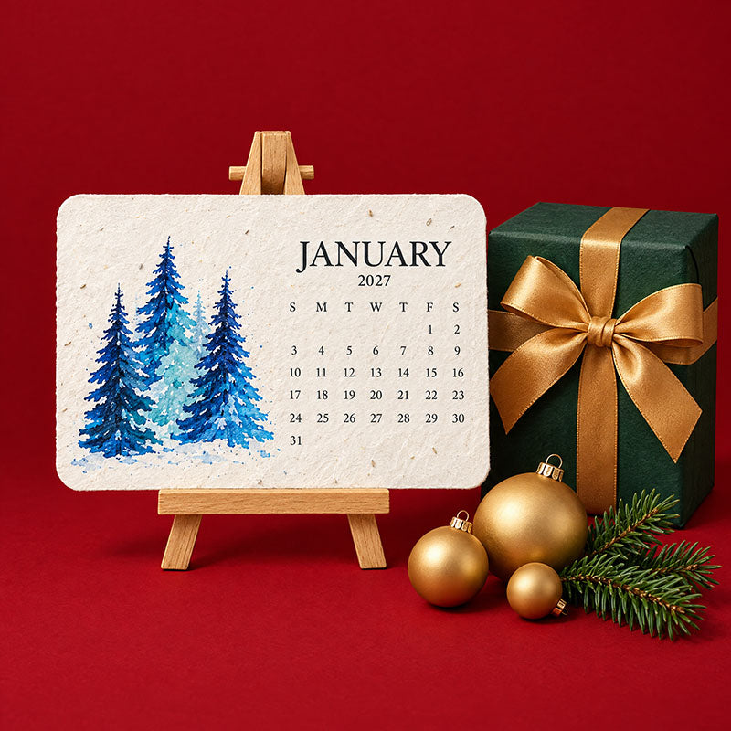 Januári, kék fenyőfás magpapír naptárlap fa állványon, zöld ajándékdoboz és arany gömbdíszek mellett 2