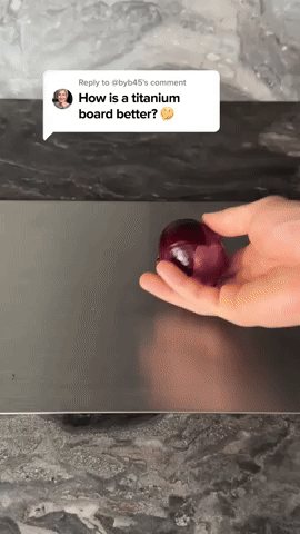 Videóképkocka, amelyen egy kéz egy lilahagymát tart a sötét, matt fémes vágódeszka felett, a kép tetején kommentbuborék látszik. 5