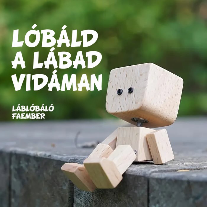 Fa figura két pici szemmel ül egy kőperem szélén zöld háttér előtt, lábát vidáman lógatva. 13