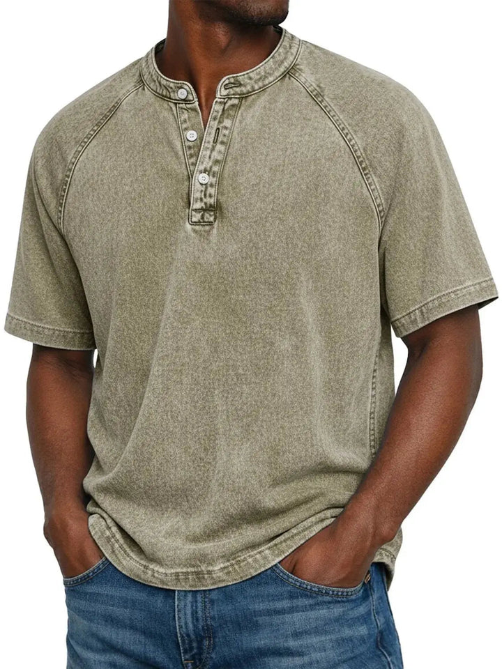 Férfi modell homokos zöldesbézs, mosott hatású Henley pólóban, raglán ujjakkal és három gombbal, elölről. 9