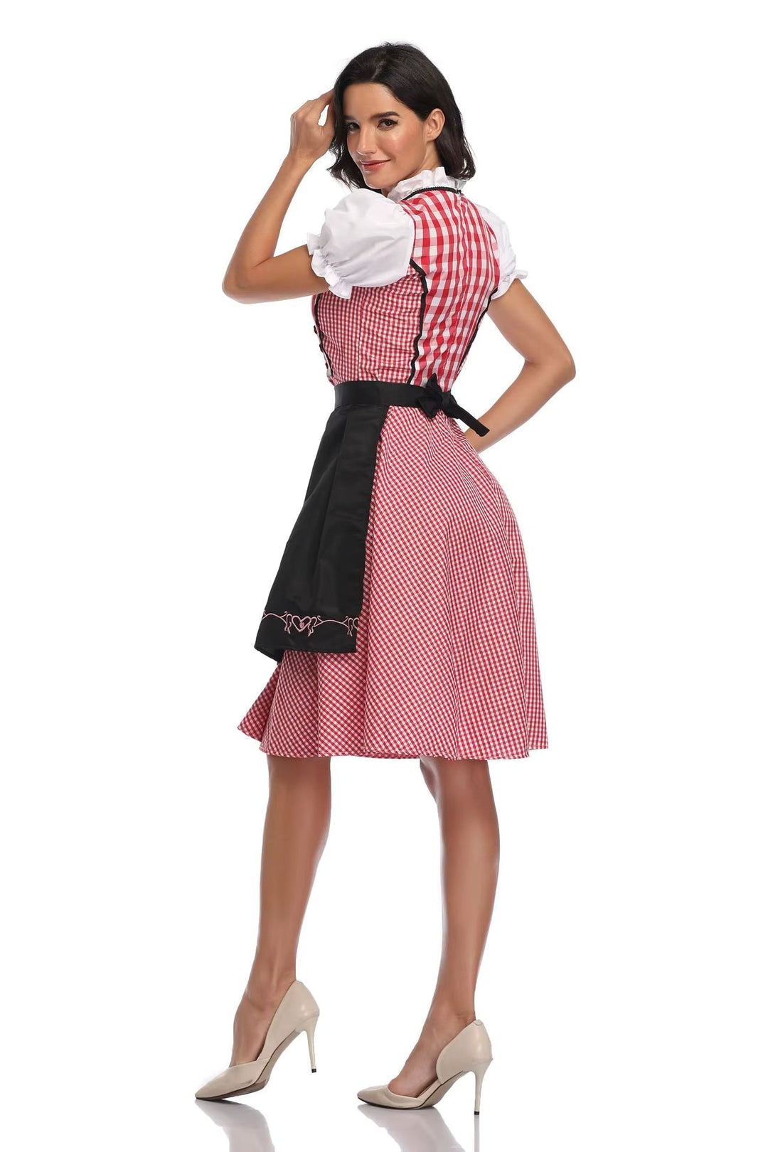 Hátulról és oldalról látszik a piros kockás dirndl fekete köténnyel, masnira kötött övvel és fehér puffos ujjú blúzzal. 2