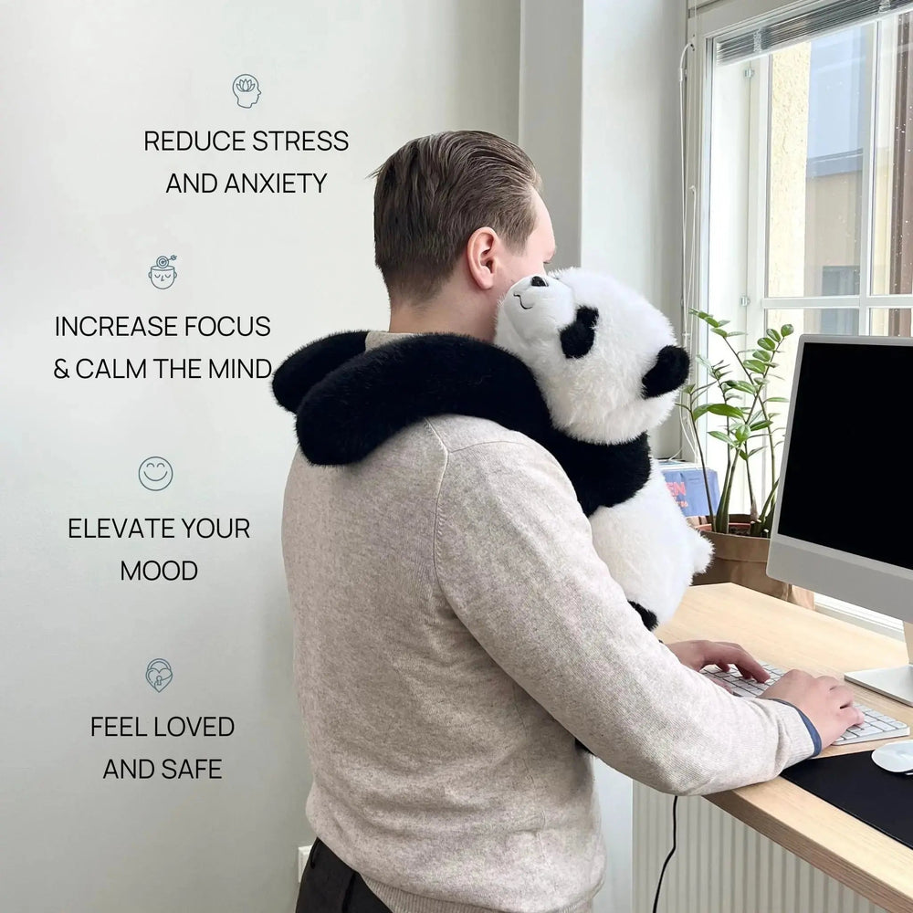 Férfi áll az íróasztalnál gépelés közben, a panda plüss hosszú karjaival a nyakába kapaszkodva a vállán pihen. 2