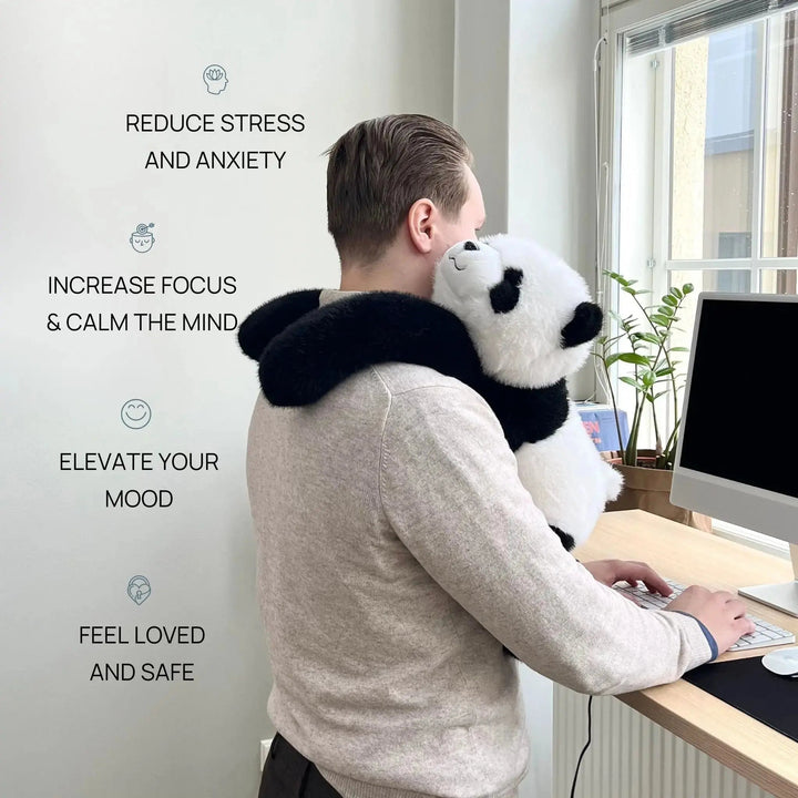 Férfi áll az íróasztalnál gépelés közben, a panda plüss hosszú karjaival a nyakába kapaszkodva a vállán pihen. 2