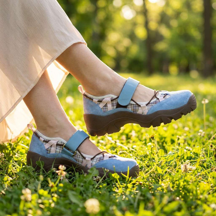 Kék velúr cipő kockás betéttel és tépőzáras pánttal, nyári fűben, könnyű szoknyás modellen. 8
