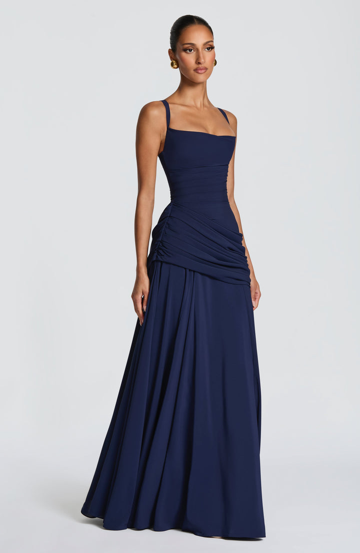 Sötétkék maxi ruha három negyed oldalnézetből, modellen, vékonyabb pántokkal, redőzött derékkal és bő szoknyával. 12